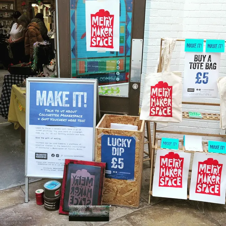Merry Makerspace tote bags and screen-printing kit outside the studio
