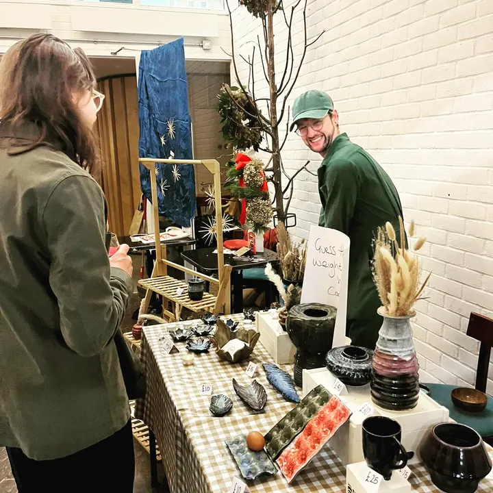 A ceramicist chatting with a shopper over his stall