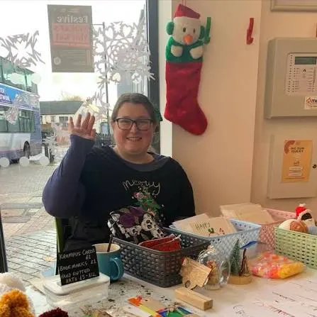 A smiling maker waving from her craft stall