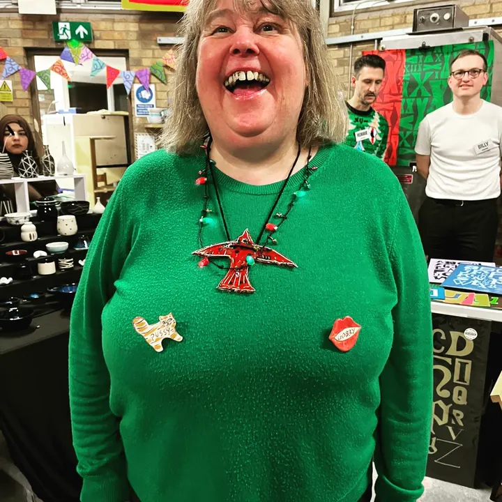A shopper in a green jumper wearing handmade ceramic brooches